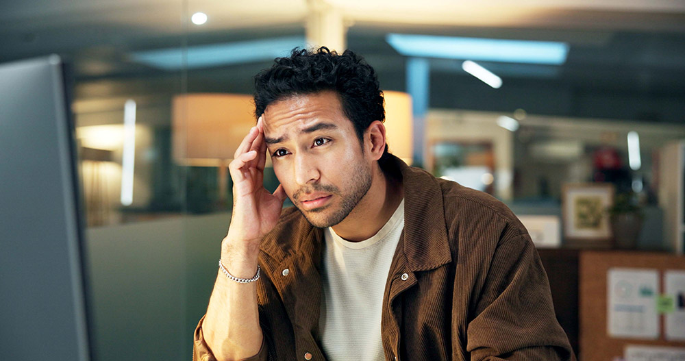 Frustrated man in a cubicle looking at a computer monitor