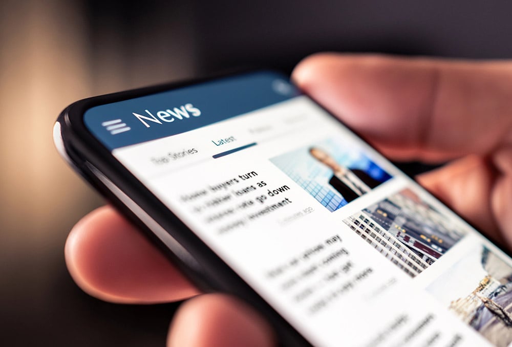 Hand scrolling through news on a smartphone